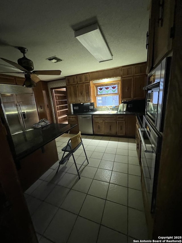 kitchen with sink, a textured ceiling, ceiling fan, and appliances with stainless steel finishes