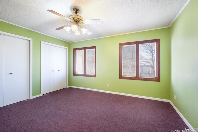 unfurnished bedroom with multiple closets, ceiling fan, carpet floors, and a textured ceiling