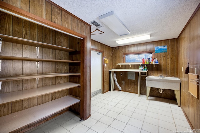 interior space with light tile patterned flooring, a textured ceiling, and wood walls