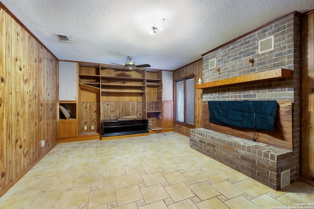 unfurnished living room with a fireplace, wooden walls, ornamental molding, and ceiling fan