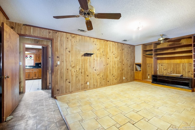 living room featuring ceiling fan, a textured ceiling, and wood walls