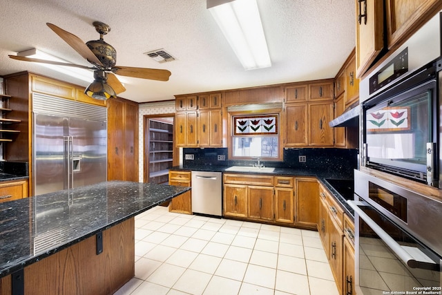 kitchen featuring stainless steel appliances, sink, light tile patterned floors, and a textured ceiling