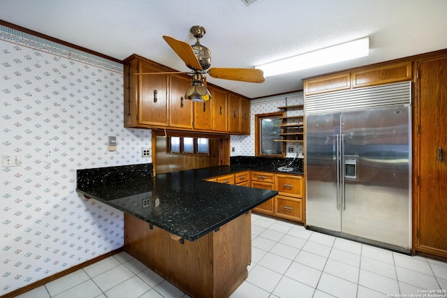 kitchen featuring light tile patterned flooring, stainless steel built in fridge, a textured ceiling, and kitchen peninsula