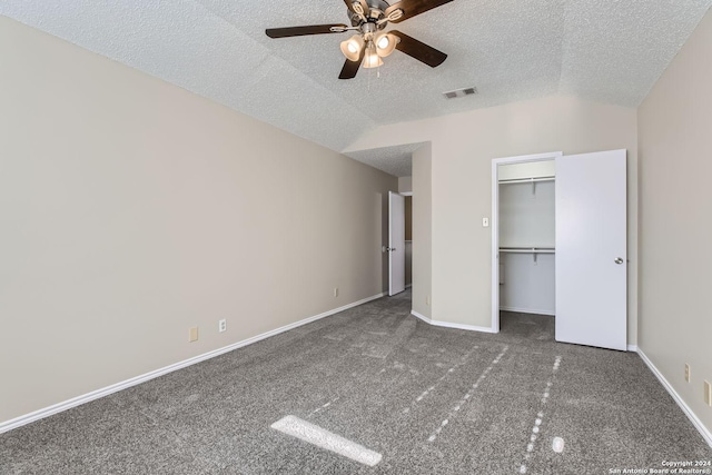 unfurnished bedroom with a textured ceiling, dark colored carpet, a closet, vaulted ceiling, and ceiling fan