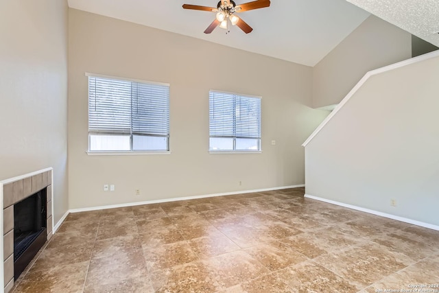 unfurnished living room with ceiling fan, a tiled fireplace, and a healthy amount of sunlight