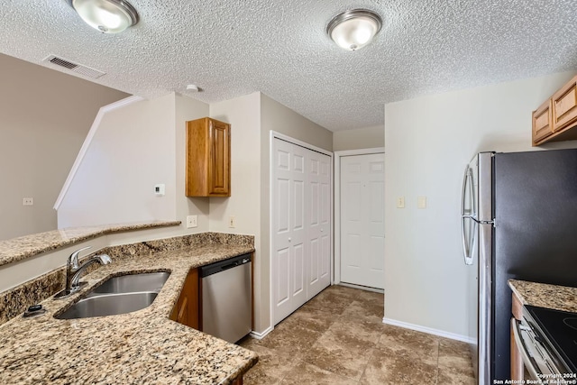 kitchen with kitchen peninsula, sink, light stone counters, a textured ceiling, and stainless steel appliances