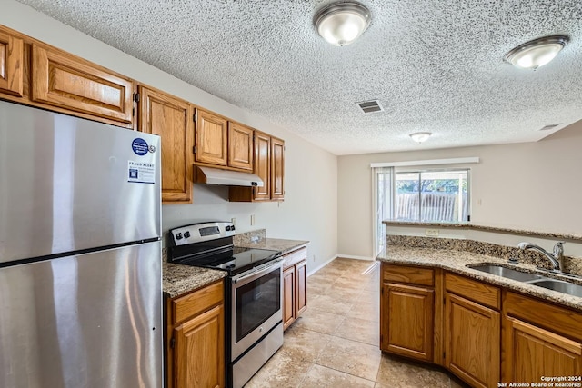 kitchen with sink, light stone counters, light tile patterned flooring, and stainless steel appliances