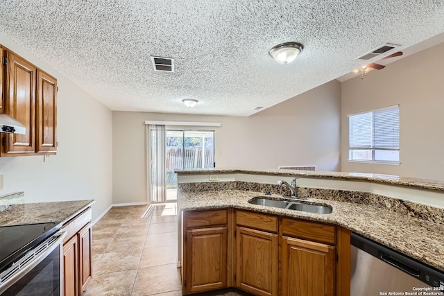 kitchen featuring sink, stone counters, light tile patterned floors, and appliances with stainless steel finishes