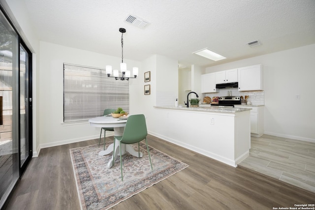 dining space with sink, a textured ceiling, dark hardwood / wood-style flooring, and an inviting chandelier