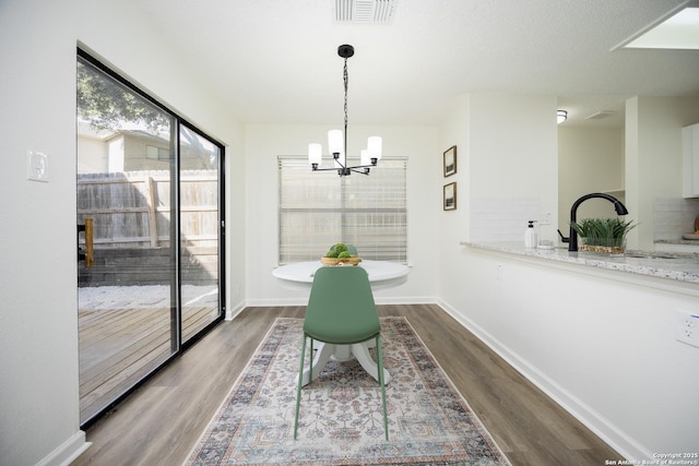 dining area with sink, hardwood / wood-style floors, and a chandelier