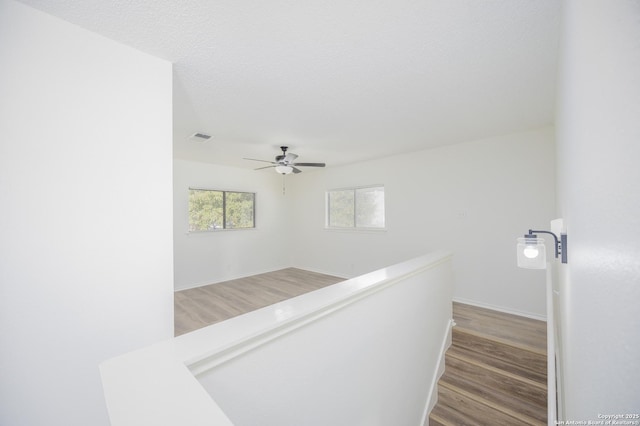 hallway with hardwood / wood-style floors and a textured ceiling