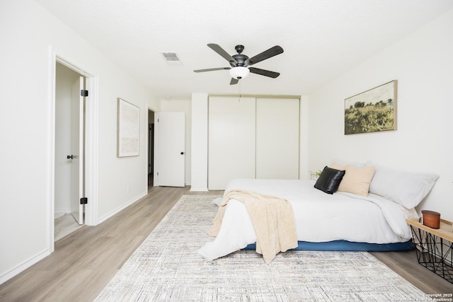 bedroom featuring light wood-type flooring, a textured ceiling, a closet, and ceiling fan