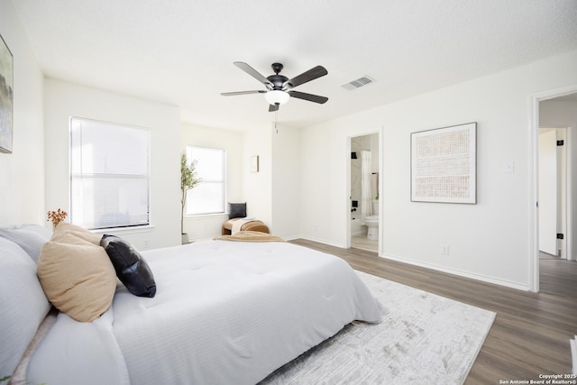 bedroom featuring dark hardwood / wood-style floors, ensuite bath, and ceiling fan