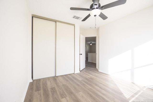 unfurnished bedroom featuring ceiling fan, a closet, and light hardwood / wood-style flooring