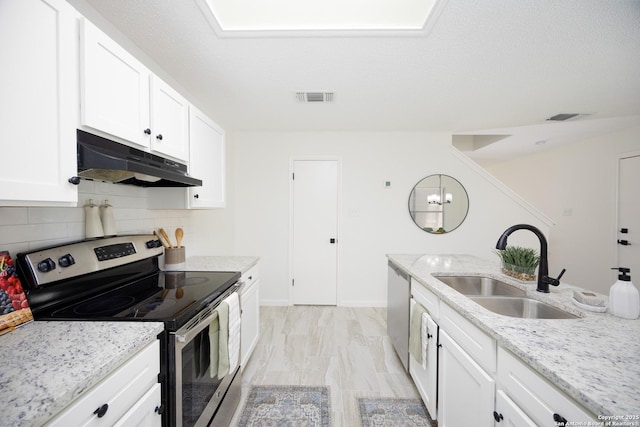 kitchen with appliances with stainless steel finishes, sink, white cabinetry, light stone counters, and decorative backsplash