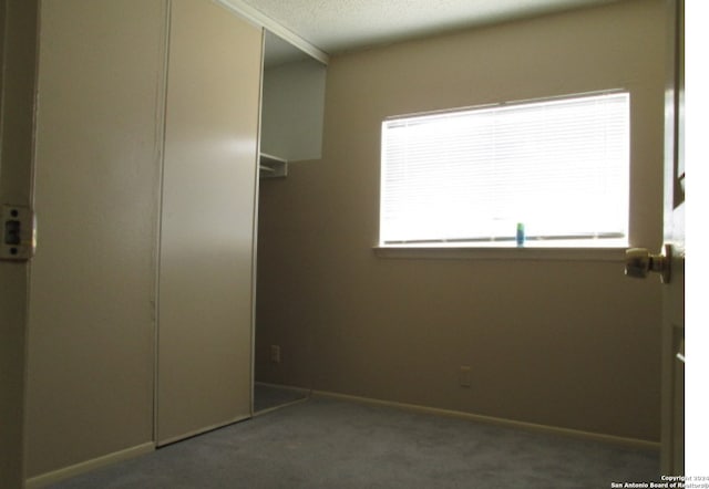 unfurnished bedroom featuring dark carpet and a textured ceiling