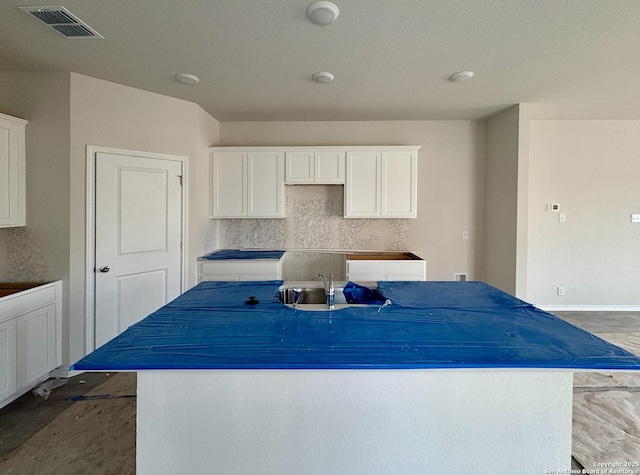 kitchen with sink, white cabinets, tasteful backsplash, and a kitchen island