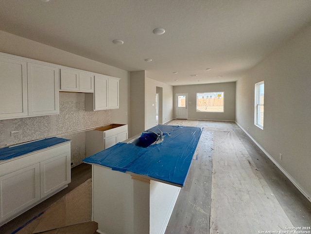 kitchen with a kitchen island, white cabinetry, and decorative backsplash