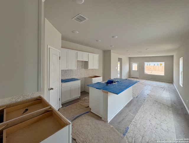 kitchen featuring a center island, backsplash, white cabinetry, and sink