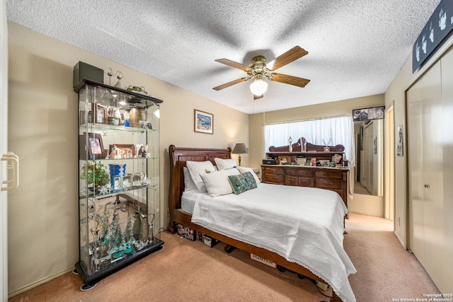 bedroom featuring ceiling fan, a textured ceiling, and light carpet