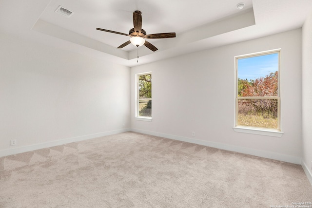 spare room with ceiling fan, carpet floors, and a tray ceiling