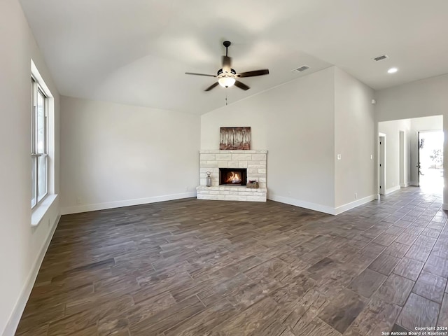 unfurnished living room featuring a wealth of natural light, lofted ceiling, and a stone fireplace