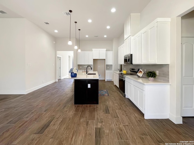 kitchen with dark hardwood / wood-style flooring, sink, appliances with stainless steel finishes, white cabinetry, and a kitchen island with sink