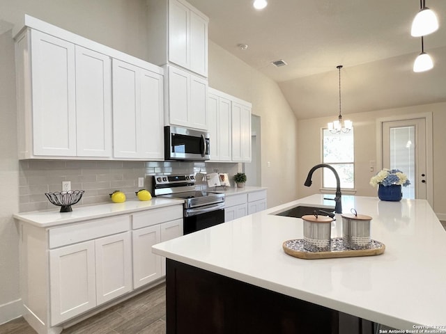 kitchen with sink, an island with sink, pendant lighting, and appliances with stainless steel finishes