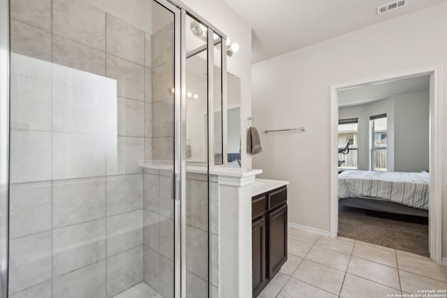 bathroom with a shower with shower door, tile patterned floors, and vanity