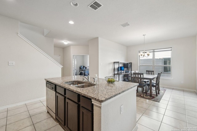 kitchen featuring dishwasher, a kitchen island with sink, light tile patterned floors, sink, and light stone counters