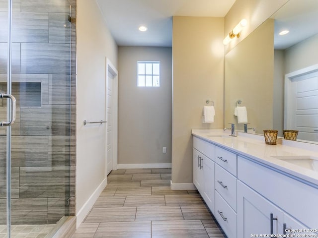 bathroom featuring a shower with door and vanity