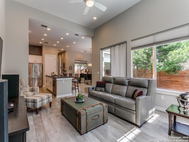 living room with sink, light wood-type flooring, and ceiling fan