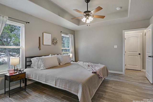 652 Canyon Bnd, Canyon Lake, TX 78133 - bedroom with multiple windows, ceiling fan, and a raised ceiling