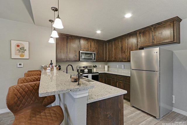 652 Canyon Bnd, Canyon Lake, TX 78133 - kitchen featuring stainless steel appliances, dark brown cabinetry, hanging light fixtures, and light stone counters
