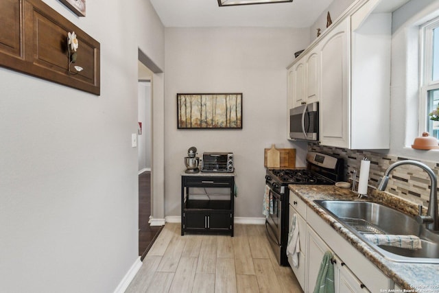 kitchen featuring white cabinets, stainless steel appliances, tasteful backsplash, light hardwood / wood-style floors, and sink