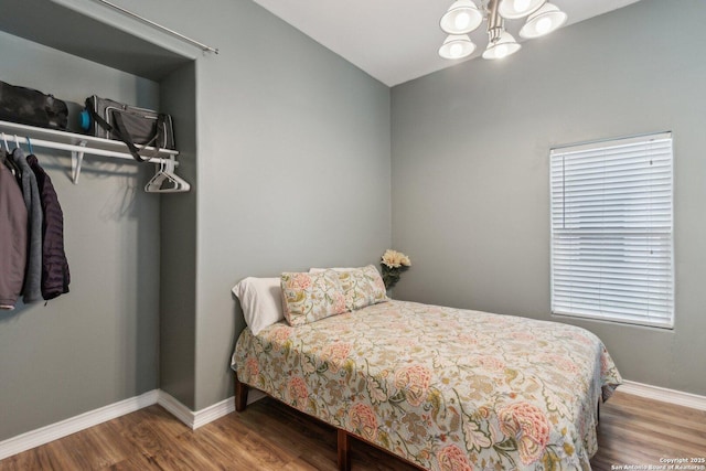 bedroom with hardwood / wood-style flooring and an inviting chandelier