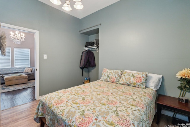 bedroom with hardwood / wood-style floors and an inviting chandelier