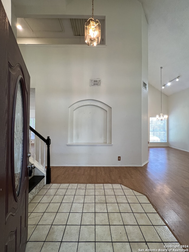 foyer featuring high vaulted ceiling, light hardwood / wood-style flooring, beam ceiling, and a chandelier