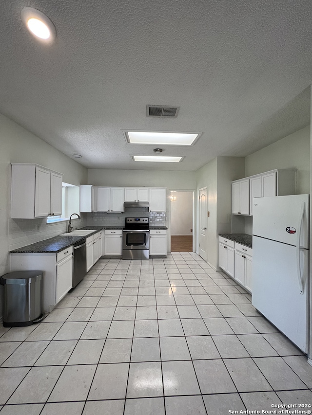 kitchen with sink, white cabinets, light tile patterned floors, a textured ceiling, and stainless steel appliances