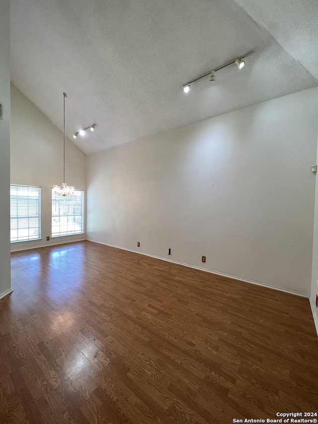 spare room with dark wood-type flooring, a textured ceiling, and an inviting chandelier