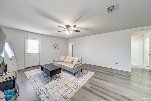 living room featuring hardwood / wood-style flooring, ceiling fan, and a textured ceiling