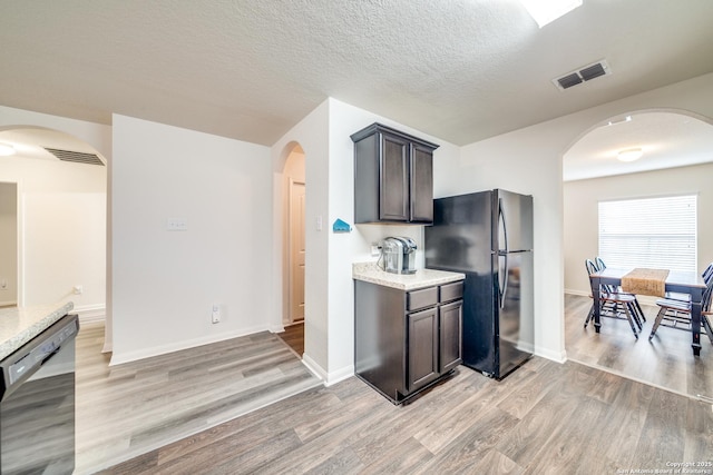 kitchen featuring light stone countertops, a textured ceiling, dark brown cabinetry, black appliances, and light hardwood / wood-style flooring