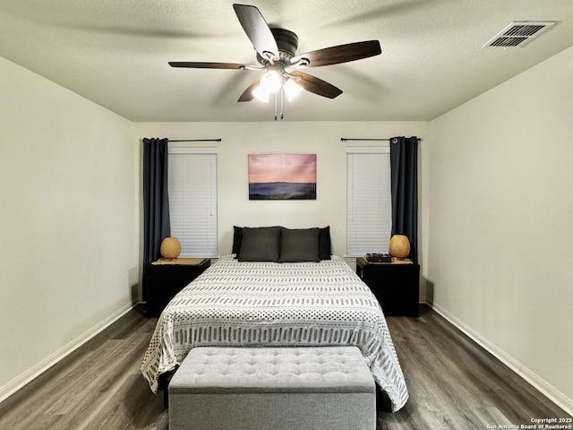 bedroom with ceiling fan, a textured ceiling, and dark hardwood / wood-style floors