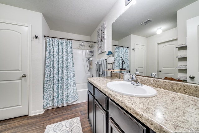 bathroom with wood-type flooring, vanity, a textured ceiling, and shower / bath combination with curtain