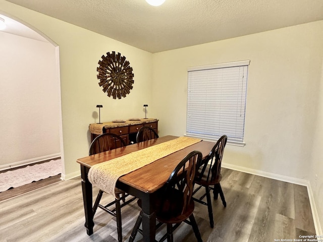 dining space with hardwood / wood-style flooring and a textured ceiling