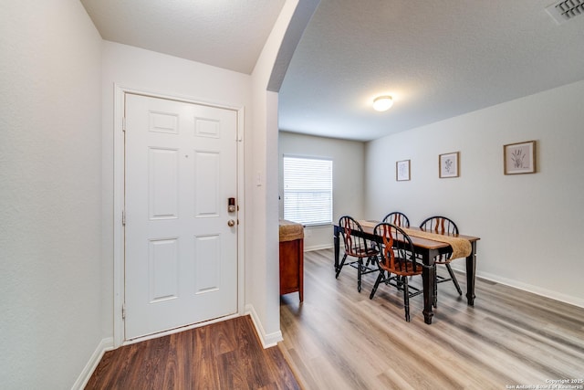 dining space featuring light wood-type flooring and a textured ceiling