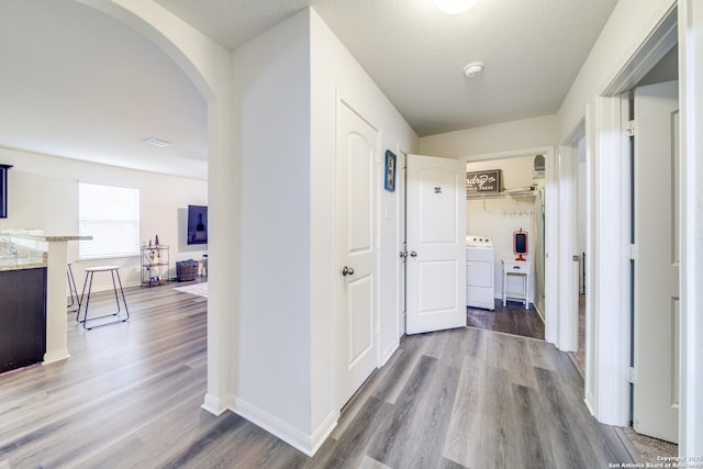 hall featuring hardwood / wood-style flooring, washer / dryer, and a textured ceiling