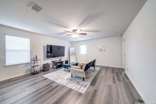 living room featuring ceiling fan, hardwood / wood-style floors, and a textured ceiling