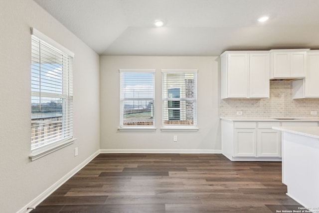 kitchen featuring tasteful backsplash, dark hardwood / wood-style floors, vaulted ceiling, and white cabinets