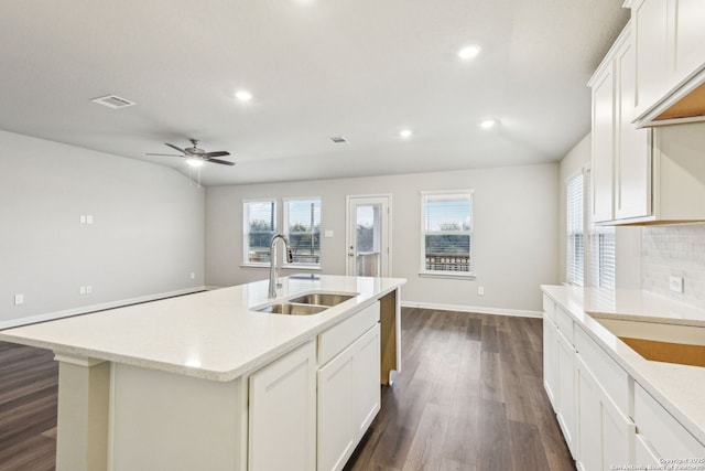 kitchen featuring tasteful backsplash, sink, white cabinets, dark hardwood / wood-style flooring, and a center island with sink